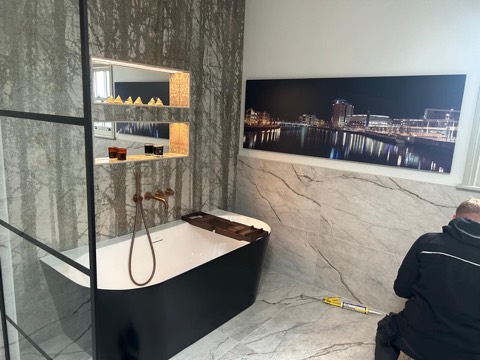Freestanding black bath, copper fittings and illuminated niches