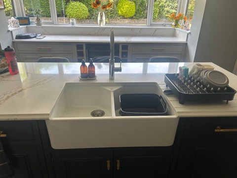 Apron-front kitchen sink and tall chrome tap in a stone island